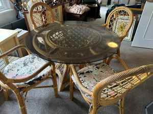 Lovely round cane dining table with glass top and four matching chairs
