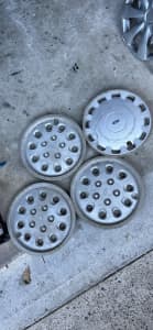 Four vintage Ford Falcon hubcaps.