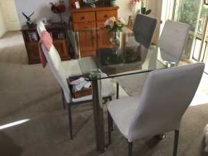 Glass top dining table with six white vinyl back chairs