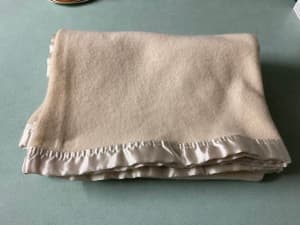 Wool? cream baby cot blanket with satin edging.