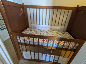 Timber baby cot with sliding gate and mattress