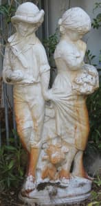 Garden statue or water feature of boy and girl he is lifting her skirt