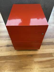 Red metal desk draw with bottom draw being a filing cabinet.