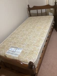 Single wooden frame bed with mattress.
