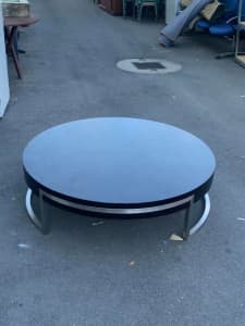 Large round low black wooden coffee table with a metal base