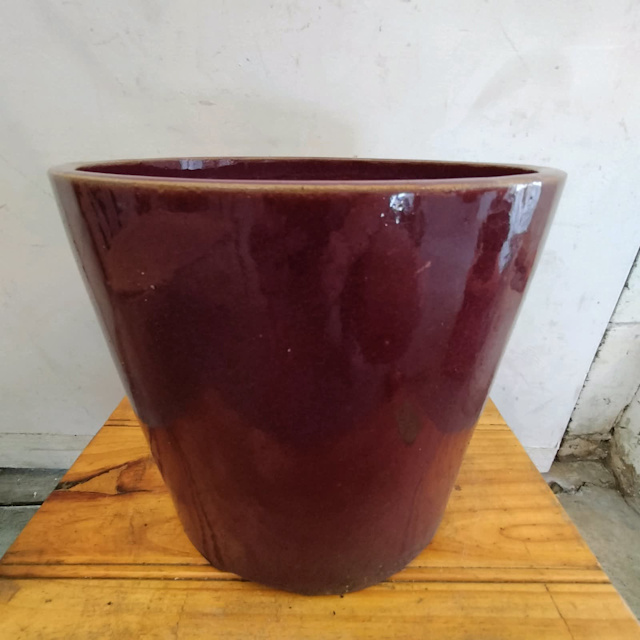 Round dark red glazed terracotta plant pot with drainage hole. Pots