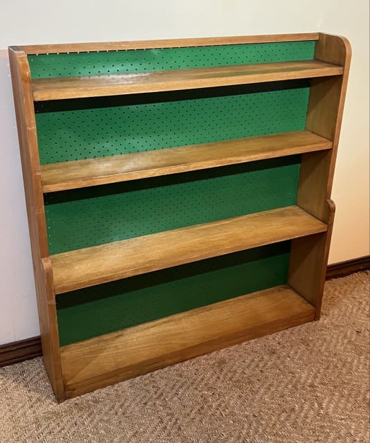 Vintage oak wooden bookcase shelves with green pegboard backing